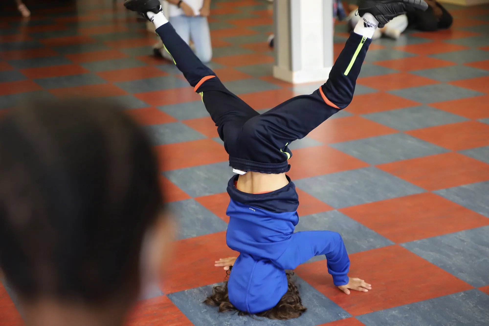 Un enfant réalise une figure de breakdance, la tête au sol